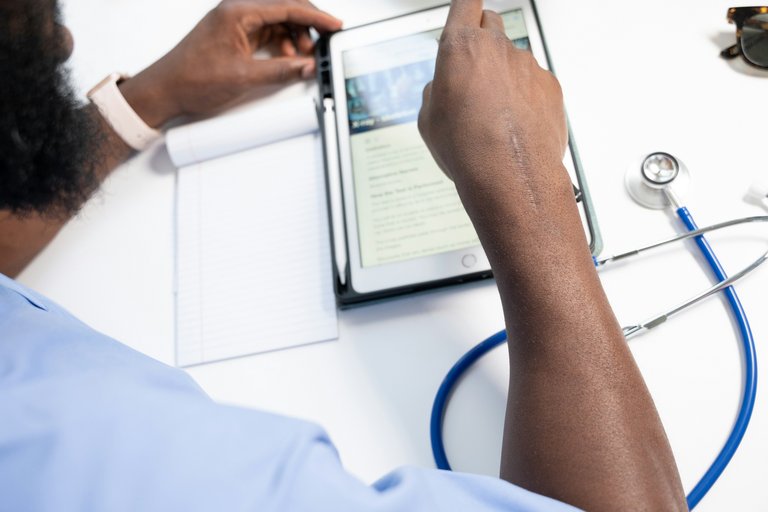 Ein Arzt bei der Arbeit mit einem Tablet. Das Bild verdeutlicht die tägliche Nutzung digitaler Endgeräte im Gesundheitswesen und unterstreicht die Notwendigkeit von sicherem, compliantem Cloud-Hosting für Patientendaten.